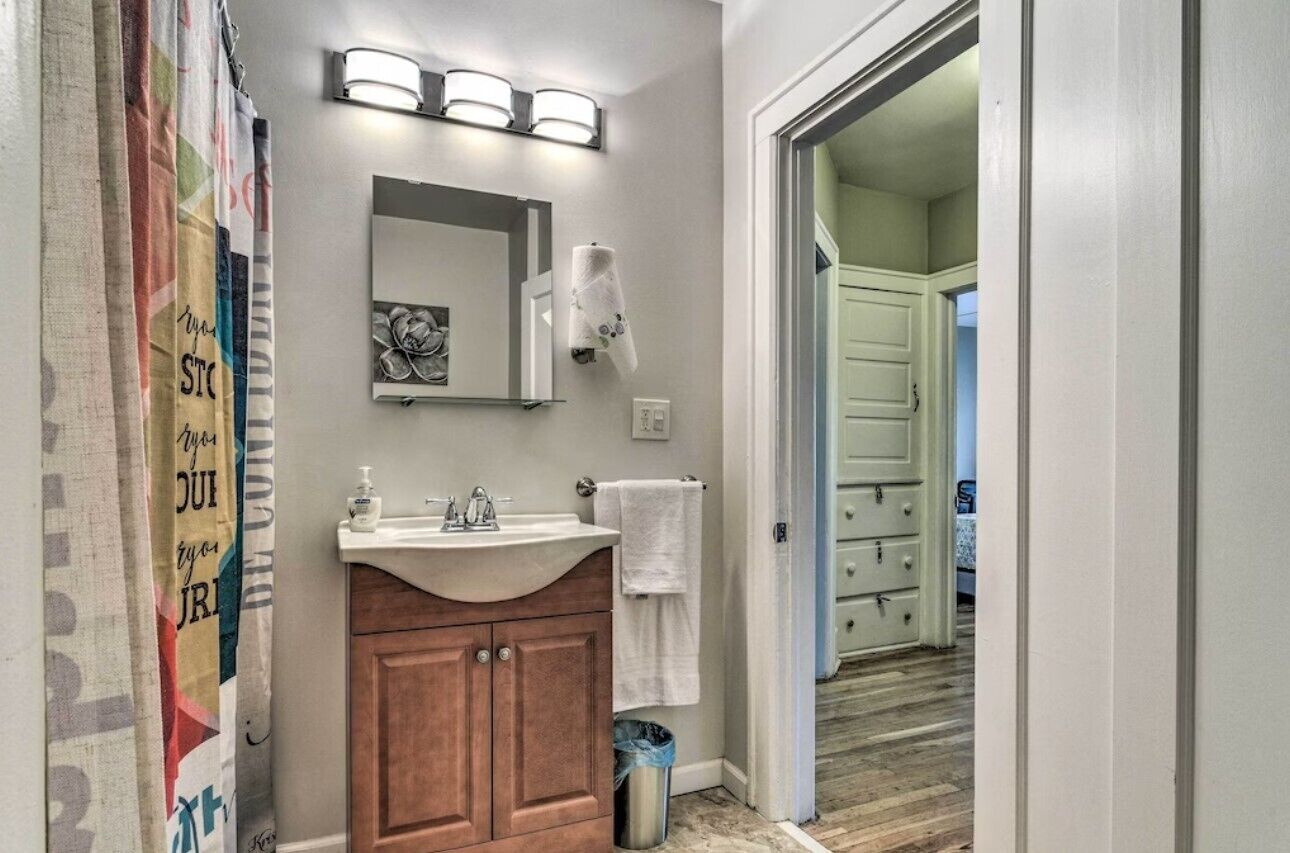 A bathroom with a wooden vanity, a sink, a mirror, and a towel rack.