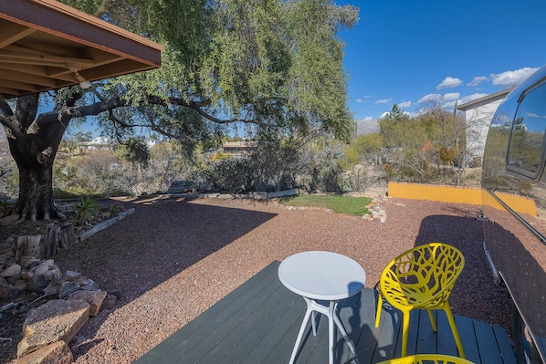 An outdoor patio with a table and chairs, surrounded by a gravel area and trees. - Economical and Private Tucson Tiny House (Tucson)