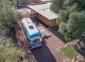 A camper parked next to a building with a deck and a small patio area.