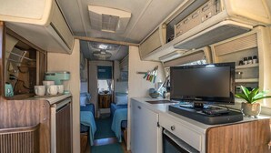 A compact RV interior with a kitchenette, a TV, and two sleeping areas. - Economical and Private Tucson Tiny House (Tucson)