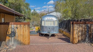 A vintage Airstream trailer parked in a rustic setting with a wooden fence and a sign reading "Casa Velo". - Economical and Private Tucson Tiny House (Tucson)