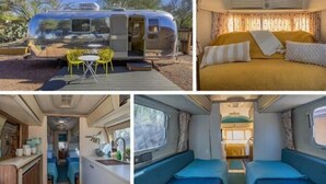 A motorhome with an outdoor seating area, a bedroom with a bed and curtains, and an interior kitchen and dining area. - Economical and Private Tucson Tiny House (Tucson)