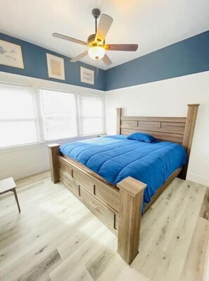 Cozy retreat with a comfortable bed, ceiling fan, and natural light pouring in through the window.
