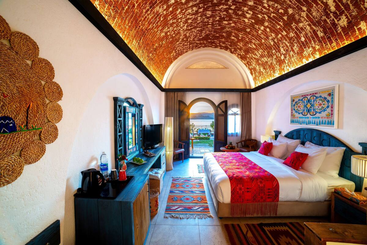 Ein Hotelzimmer mit Bett, Fernseher, Schreibtisch und Blick ins Freie.