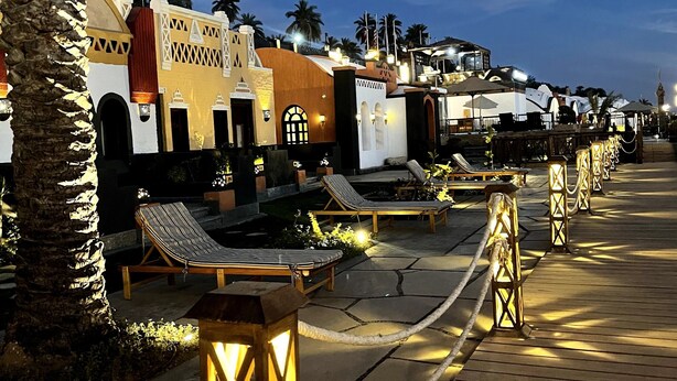 Een resort met buitenzitgedeeltes, palmbomen en een houten terras.