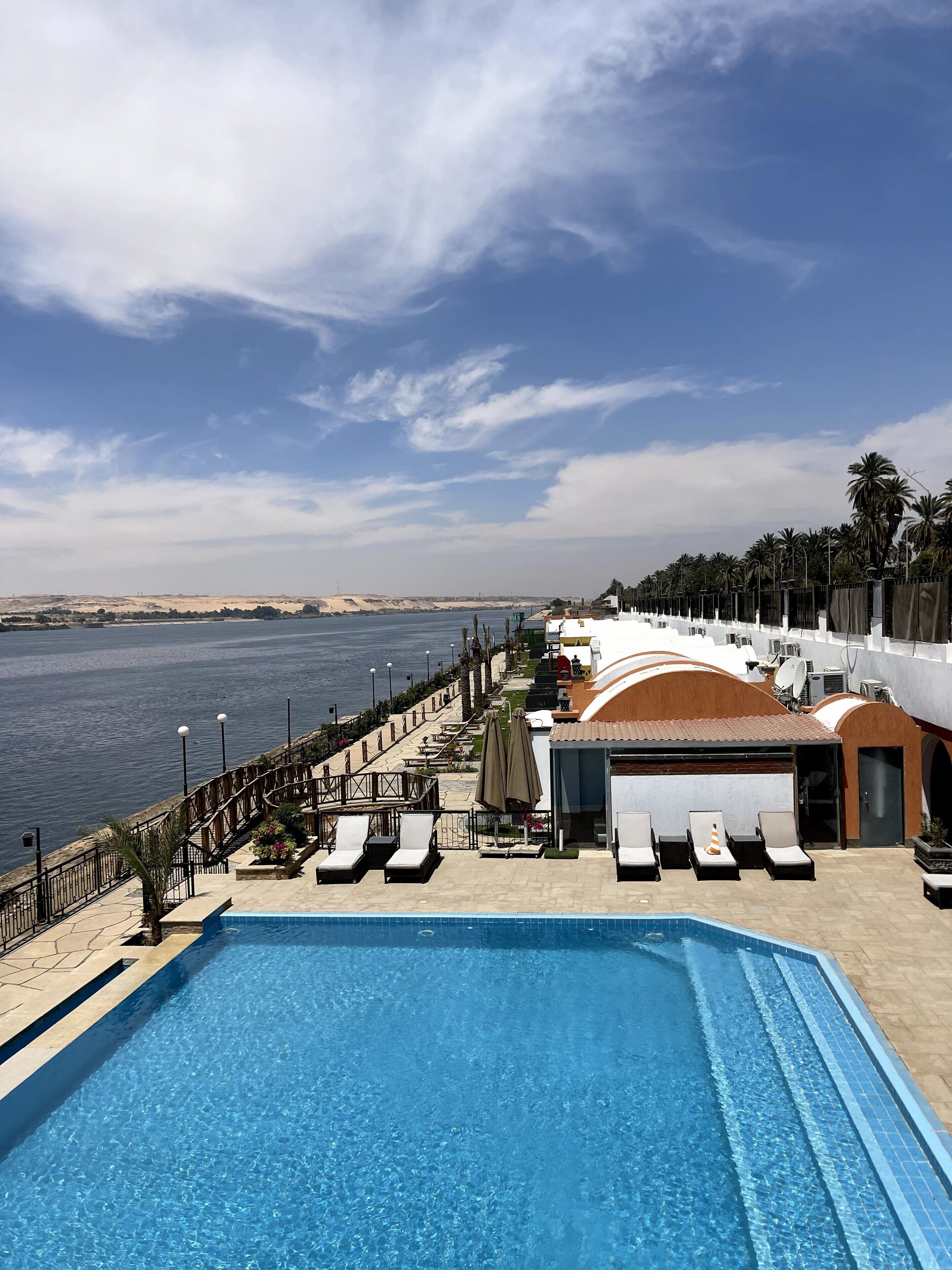 Zona de piscina con sillones de descanso y vista al mar.