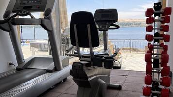 A gym with treadmills, a stationary bike, and a set of red dumbbells.