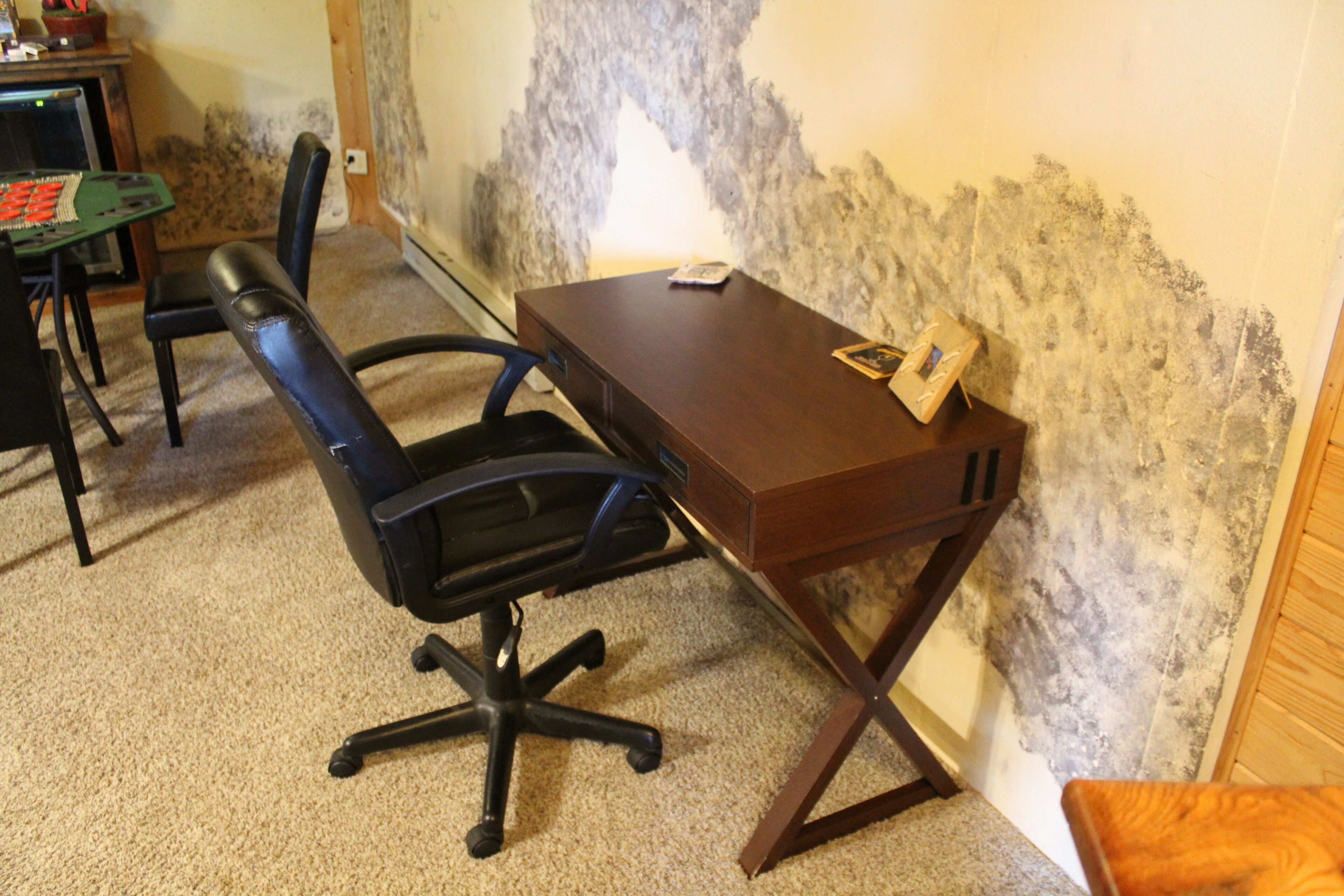 A small office with a desk, chair, and a wall with a textured surface.