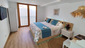 Ein Schlafzimmer mit Bett, Nachttisch, Lampe und einem kleinen Tisch mit Pflanze.