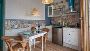Eine Küche mit Esstisch, Korbstühlen, einem Kühlschrank, einer Mikrowelle und einem Herd.