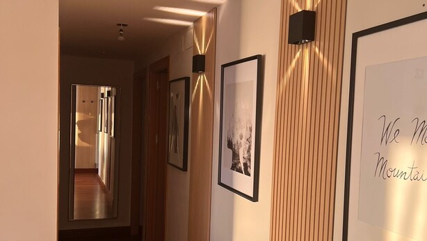 A hallway with wooden paneling, framed artwork on the walls, and a wooden floor. - Modern centrally located apartment mall pools and private parking (Torremolinos)