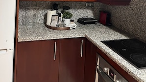 A kitchen with dark wooden cabinets, a stainless steel microwave, a granite countertop, and a built-in oven. - Modern centrally located apartment mall pools and private parking (Torremolinos)