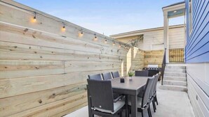 An outdoor patio with a dining table and chairs, a wooden fence, and a kitchen area. - Lux and Spacious for Groups near French Quarter (New Orleans)
