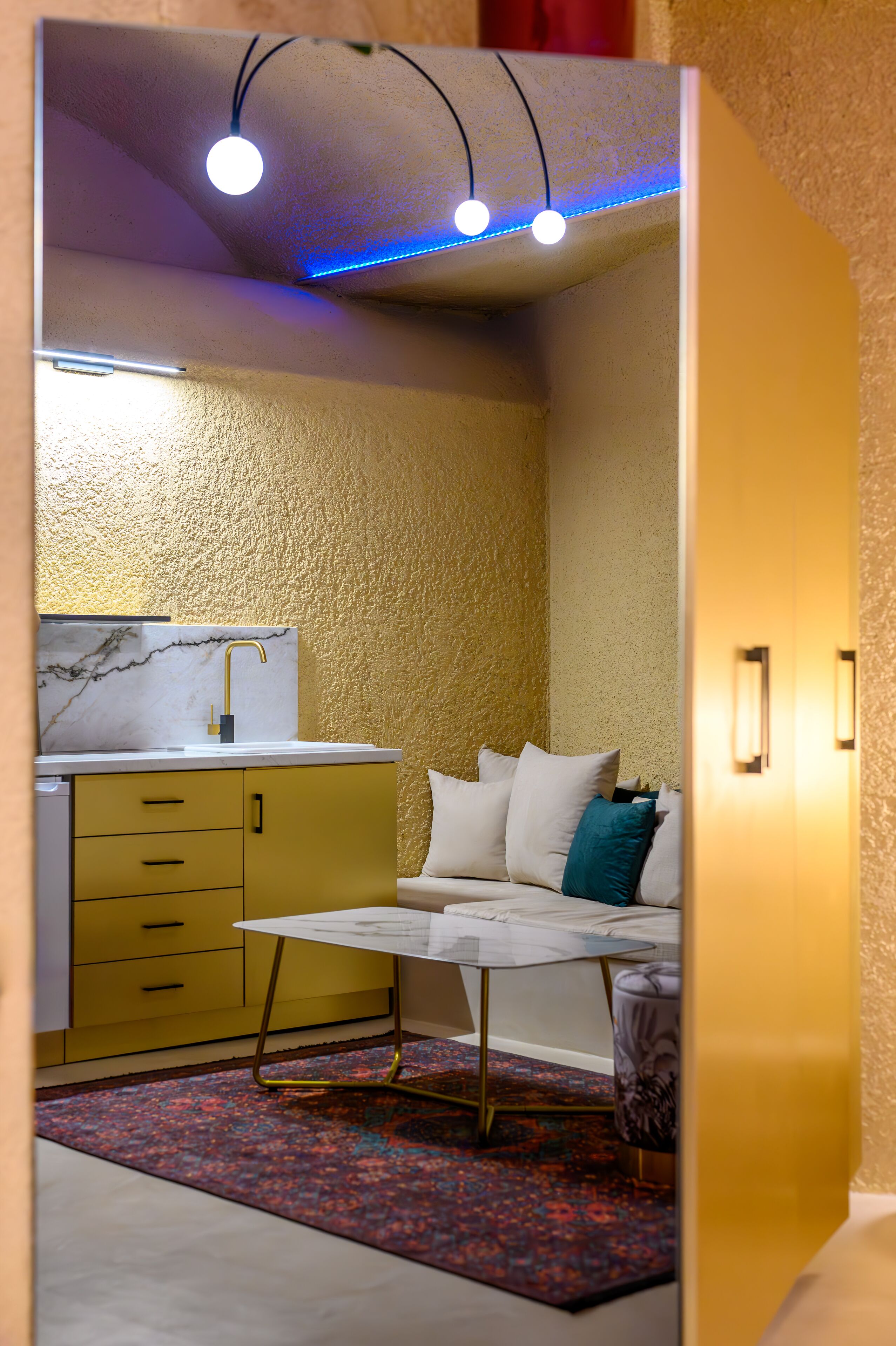 A compact room with a bed, a small table, a sink, and a cabinet.