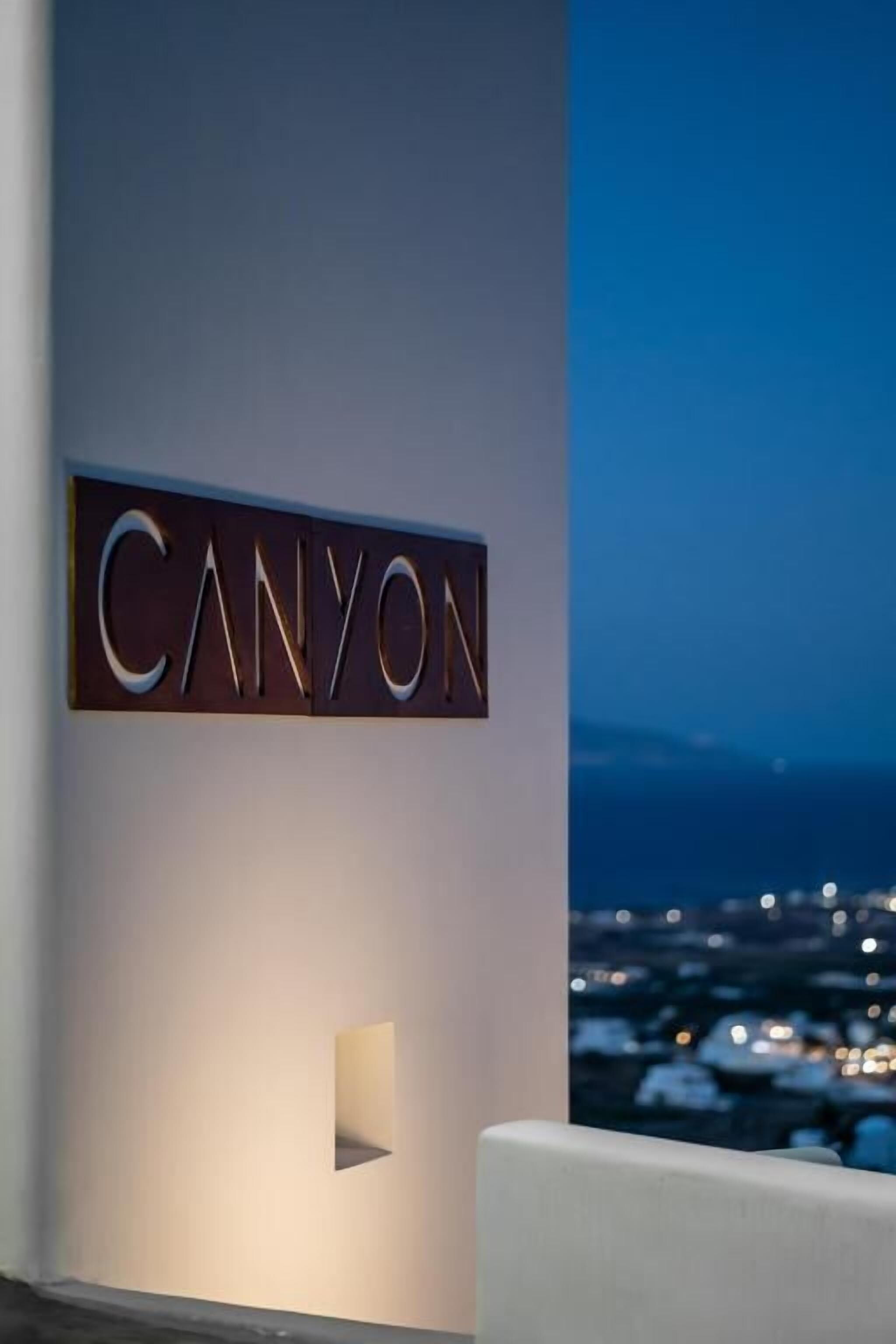 A modern hotel sign with the word "CANYON" illuminated against a night sky.