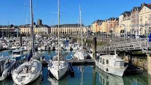 Un puerto deportivo con varias embarcaciones amarradas, un puente y edificios históricos al fondo.