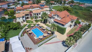 A residential area with a swimming pool surrounded by lounge chairs and umbrellas, indicating a private outdoor space.