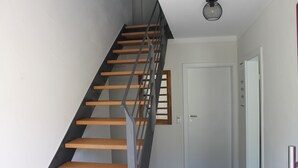 A modern staircase with wooden steps and metal railings leading to a white door. - Vacation apartment in Gerolstein, with a view of the Dolomites, up to 8 people (Gerolstein)
