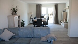 A living room with a sofa, a dining table with chairs, a TV, and a plant. - Vacation apartment in Gerolstein, with a view of the Dolomites, up to 8 people (Gerolstein)