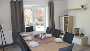 A dining area with a wooden table set for six, surrounded by chairs. - Vacation apartment in Gerolstein, with a view of the Dolomites, up to 8 people (Gerolstein)