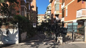 A gated entrance to a residential area with a no parking sign, a metal gate, and a building with balconies.