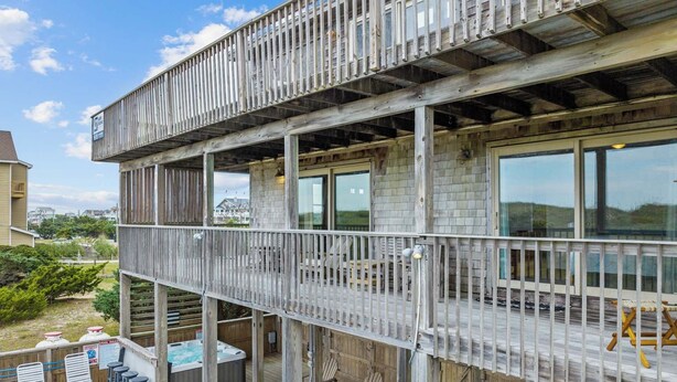 A multi-level wooden structure with outdoor seating and a hot tub. - Oceanfront Home in Waves with Pool, Hot Tub, and Game Room (Waves)