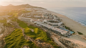 Oversigtsbillede af et resort med flere bygninger, en strand og en golfbane.