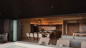 Un soggiorno moderno con una grande vasca da bagno bianca, un'area pranzo con sedie di legno e una cucina sullo sfondo.