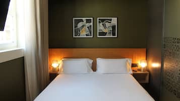 A hotel room with a large bed, two bedside lamps, and abstract artwork on the wall.
