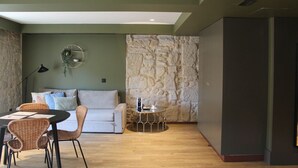 Een moderne woonkamer met een stenen accentmuur, een ronde salontafel en een bank met kussens.
