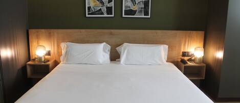 A hotel room with a large bed, two bedside tables with lamps, and abstract art on the wall.
