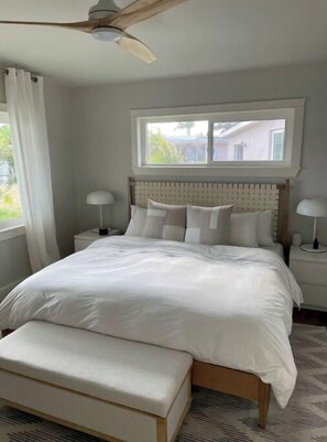 Relax in a spacious bedroom with a large bed, bench, and ceiling fan.