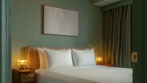 A neatly made bed with white linens, a wooden headboard, and two bedside lamps. - Condo On The Beach - Heated Pool - Self Check-in (Belleair Beach)