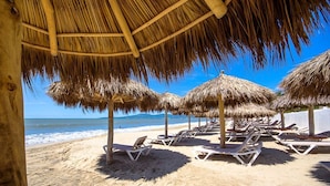 A beach with thatched umbrellas and sun loungers. - Modern- Renovated- Breathtaking 6th Floor- 3 Bedrooms Villa Magna (Nuevo Vallarta)