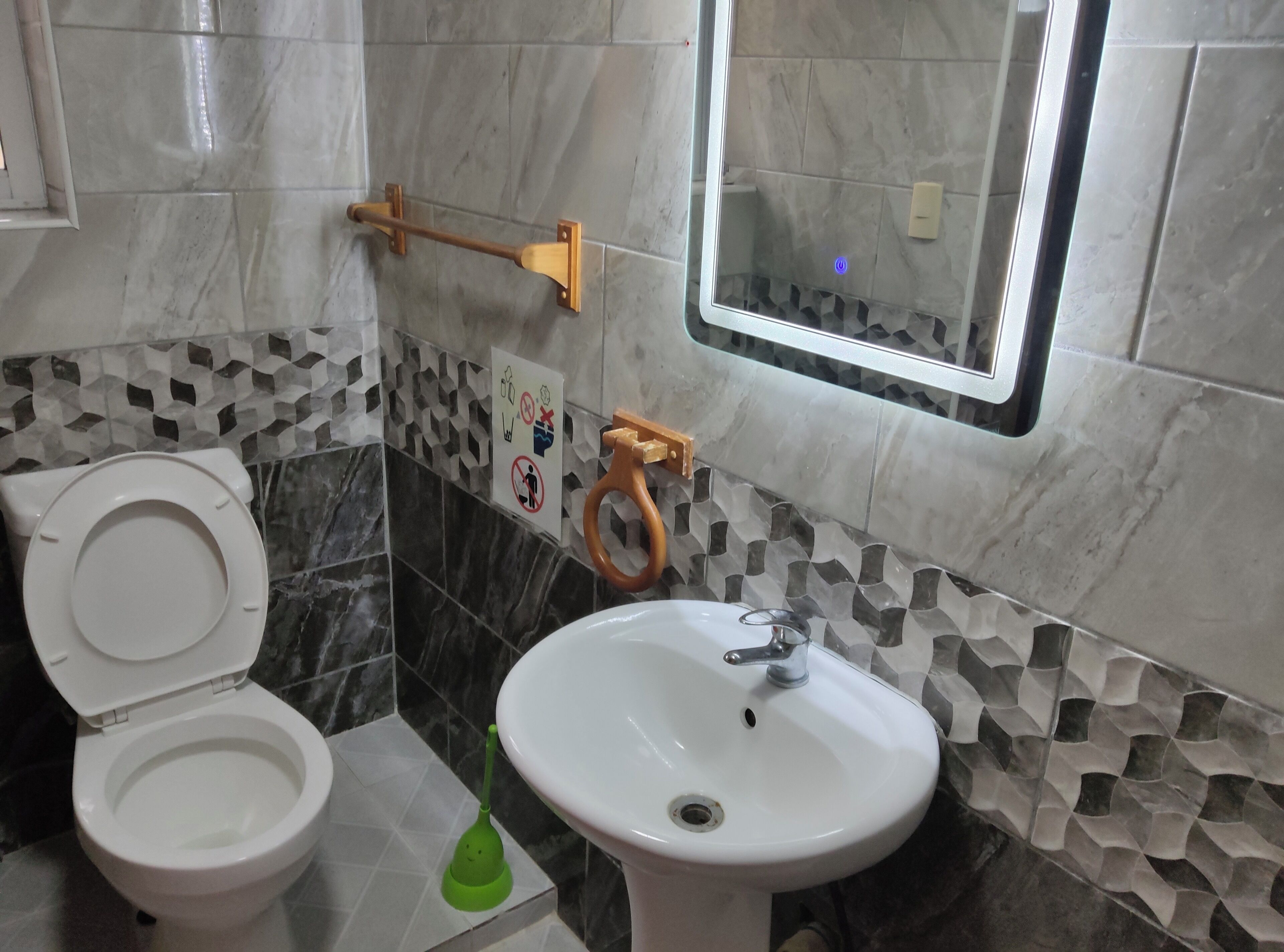Et badeværelse med toilet, vask og en vægmonteret håndtørrer.