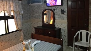 A bedroom with a bed, a dresser, a mirror, a television, and a chair. - Apart-Hotel Costa Verde Distrito Nacional (Santo Domingo Oeste)