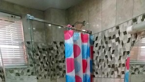 A bathroom with a glass shower enclosure, a white sink, and a patterned shower curtain. - Apart-Hotel Costa Verde Distrito Nacional (Santo Domingo Oeste)