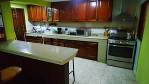 A kitchen with wooden cabinets, a microwave, a stove, and a sink.