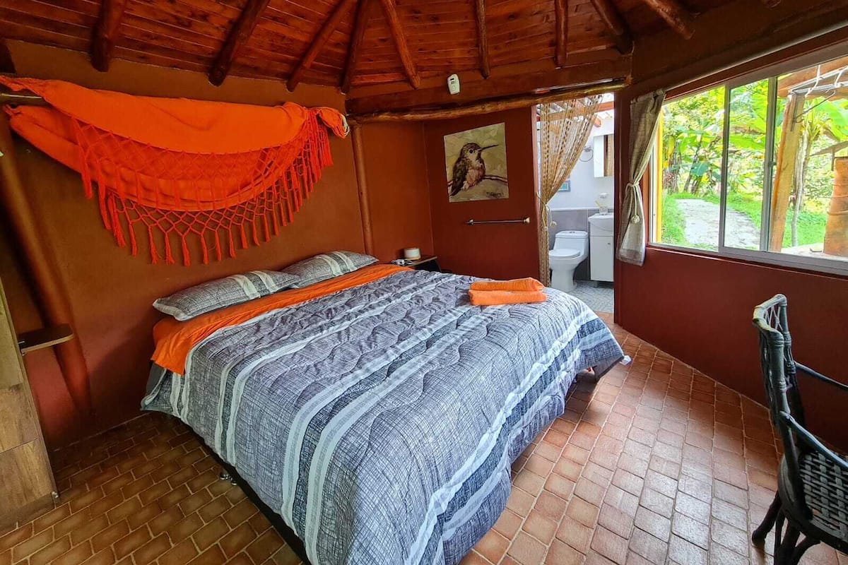 A room with a bed, a window, and a door leading to a bathroom.