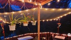 An outdoor patio area with string lights, wooden tables, chairs, and potted plants. - Athaka'i (Concepción)