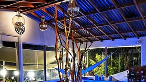 A modern kitchen with a blue-lit bar area, a dining table with chairs, and a large window overlooking greenery. - Athaka'i (Concepción)