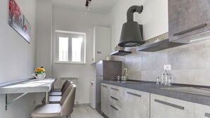 A modern kitchen with a grey countertop, stainless steel appliances, and a window providing natural light. - Voyager House (Rome)