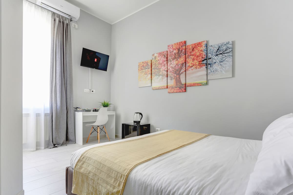 A modern hotel room with a bed, a desk, and a TV.