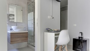 A modern bathroom with a white sink, wooden vanity, and a glass shower enclosure. - Voyager House (Rome)