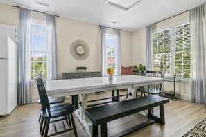 Een moderne keuken met een groot eiland, witte kasten, en een zithoek met een bank en stoelen.