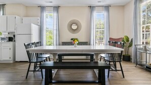 Une cuisine moderne dotée d’un grand îlot central, de meubles blancs et d’un coin repas avec une banquette et des chaises.