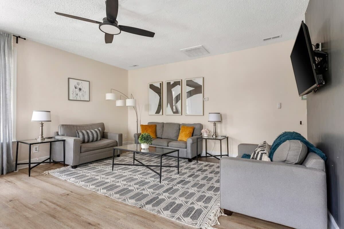 A modern living room with a grey sofa, a coffee table, and a TV mounted on the wall.