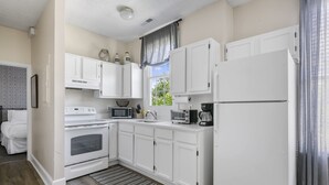 Une cuisine moderne avec des meubles blancs, une cuisinière, un four à micro-ondes, un grille-pain et un réfrigérateur.