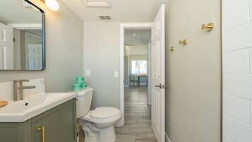 A bathroom with a toilet, sink, and mirror.