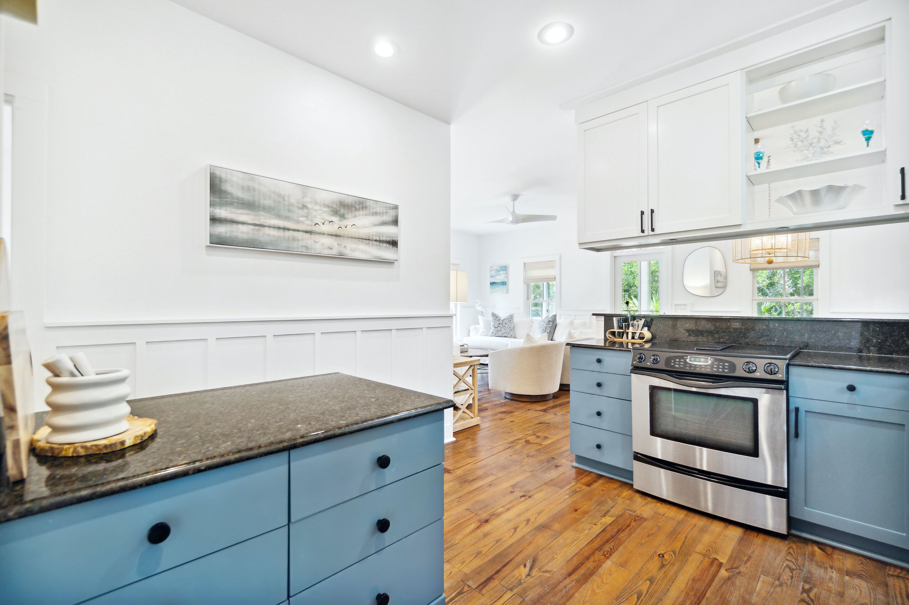 A modern kitchen with white cabinetry, a stainless steel oven, and a marble countertop.